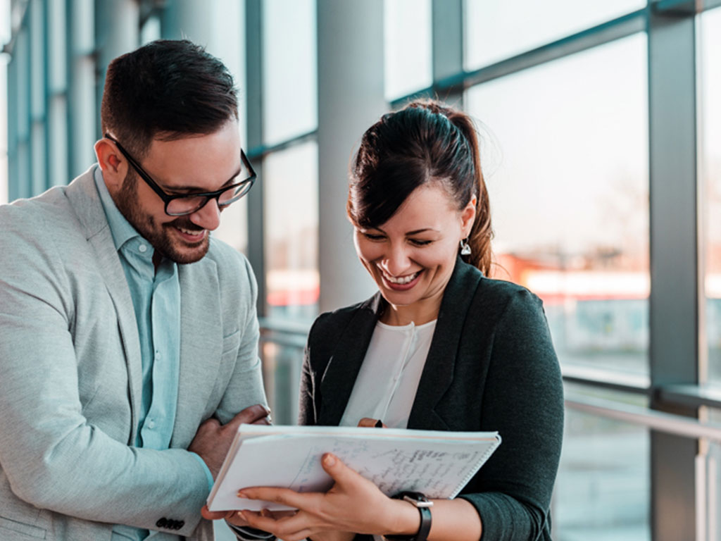 two people looking at notebook smiling