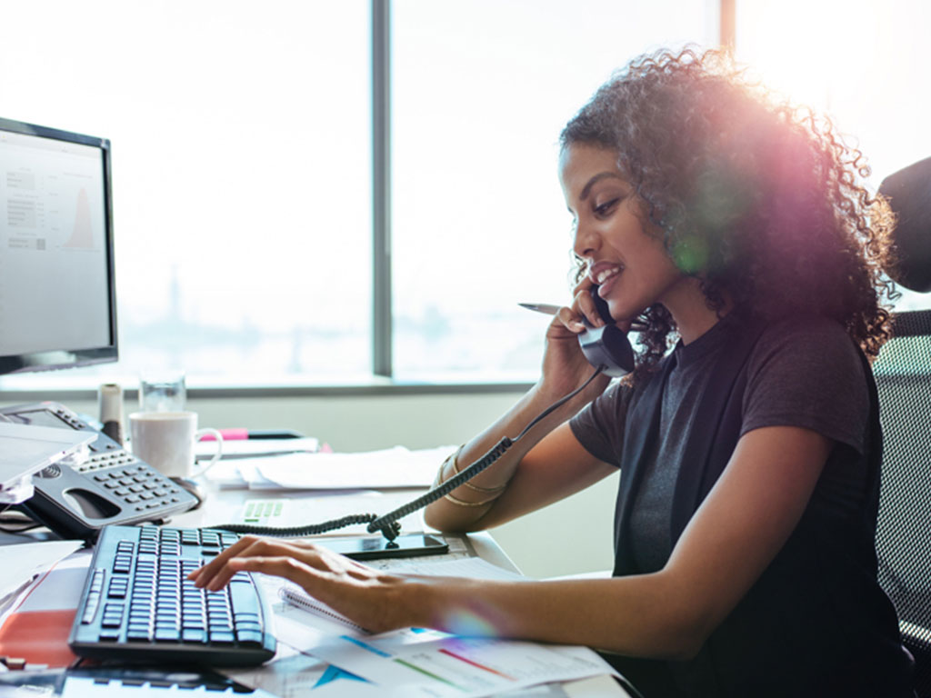 female on phone typing on computer